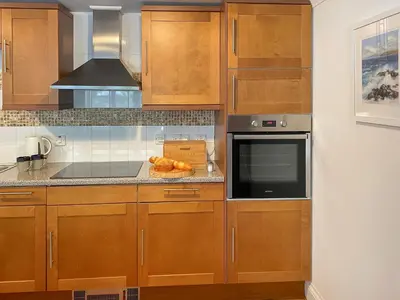 a kitchen with wooden cabinets and a stove top oven at Dune Cottage - Uk48934 in Saint Erth