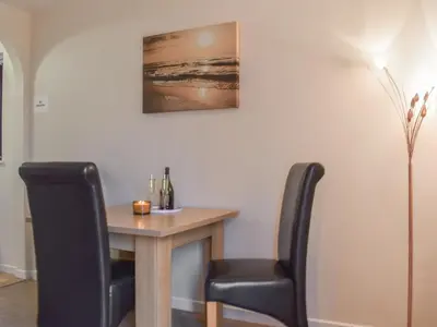a dining room table with two black chairs and a table with a bottle of wine at Milking Parlour - Uk49026 in Liskeard