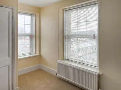 an empty room with two windows and a radiator at The Farmhouse - Uk49068 in Liskeard