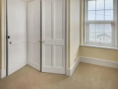 a room with white closet doors and a window at The Farmhouse - Uk49068 in Liskeard