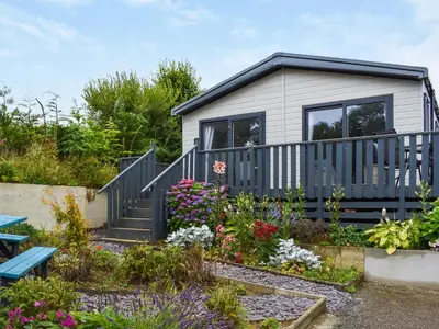 a tiny house with a garden and flowers at Edmonton Lodge - Uk50308 in Doublebois