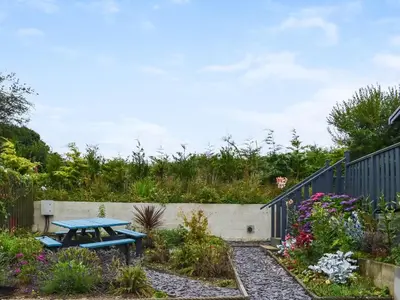a picnic table in a garden with a fence at Edmonton Lodge - Uk50308 in Doublebois