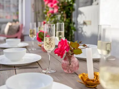 a wooden table with wine glasses and a vase with flowers at Geranium Cottage in Port Isaac
