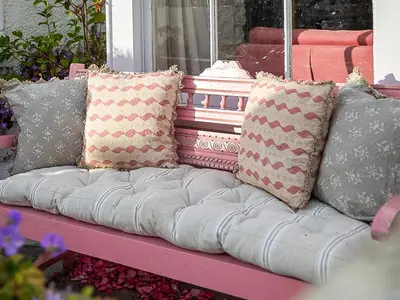 a pink couch with several pillows on it at Geranium Cottage in Port Isaac