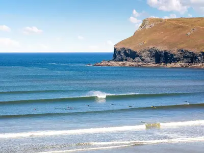 a group of people riding waves in the ocean at Geranium Cottage in Port Isaac