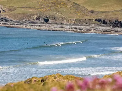 a group of people surfing on the waves in the ocean at Geranium Cottage in Port Isaac