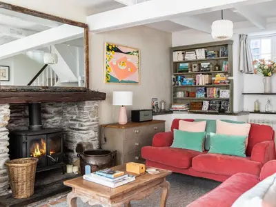a living room with a red couch and a fireplace at Geranium Cottage in Port Isaac