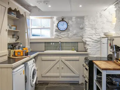 a kitchen with a sink and a clock on the wall at Geranium Cottage in Port Isaac