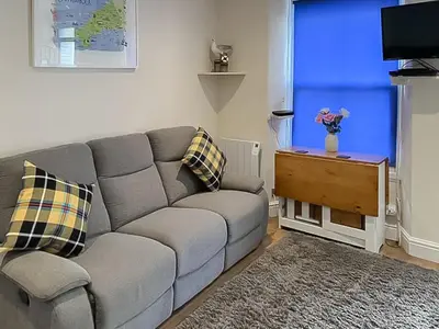 a living room with a gray couch and a blue wall at Seagull Cottage in Looe
