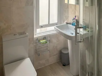 a bathroom with a sink and a toilet and a window at Seagull Cottage in Looe