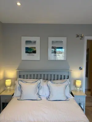 a bedroom with a white bed with two lamps and two pictures at Porthtowan Guest Suite in Porthtowan
