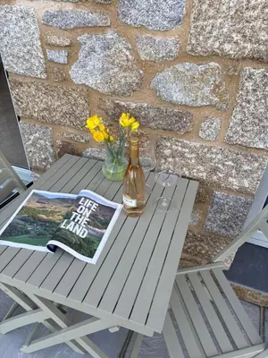 a picnic table with a book and a bottle of beer at Porthtowan Guest Suite in Porthtowan