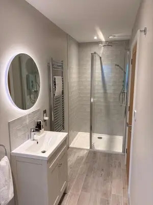 a white bathroom with a shower and a sink at Porthtowan Guest Suite in Porthtowan
