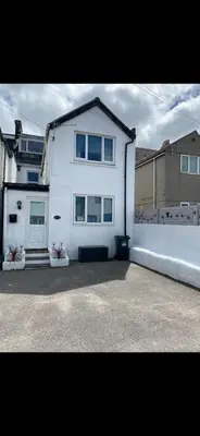 a white house with three windows on a driveway at Sunset Apartments Newquay in Newquay