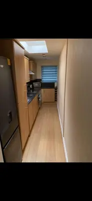 a small kitchen with wooden floors and a hallway at Sunset Apartments Newquay in Newquay