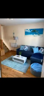 a living room with a blue couch and a table at Sunset Apartments Newquay in Newquay