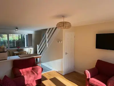 a living room with two chairs and a tv and a staircase at Entire 2 bedroom house in a great Cornish location in Saint Columb Road Station