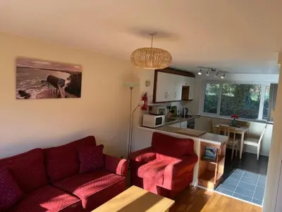 a living room with two red couches and a kitchen at Entire 2 bedroom house in a great Cornish location in Saint Columb Road Station