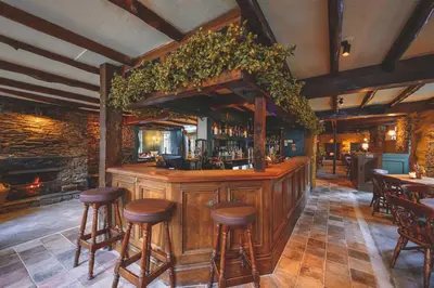 a bar in a restaurant with wooden stools at The Copley Arms in Downderry