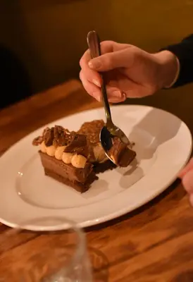 a person eating a piece of cake on a plate with a fork at The Copley Arms in Downderry