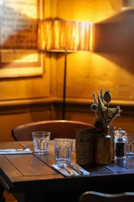 a wooden table with glasses and a plant on it at The Copley Arms in Downderry
