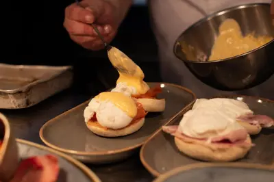a person is serving food on plates with ice cream at The Copley Arms in Downderry
