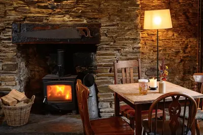 a dining room with a table and a wood stove at The Copley Arms in Downderry