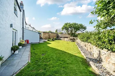 a garden with a stone wall next to a house at Idyllic Cornish House in St. Agnes