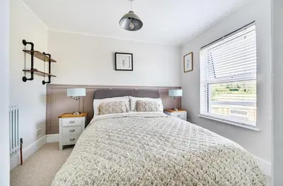 a bedroom with a bed and two lamps and a window at Idyllic Cornish House in St. Agnes