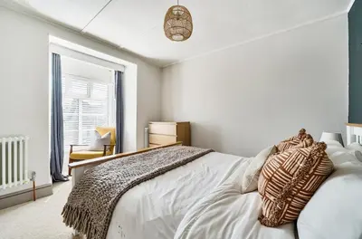 a bedroom with a white bed and a window at Idyllic Cornish House in St. Agnes