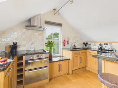 a large kitchen with wooden cabinets and stainless steel appliances at The Crows Nest – Sea View Retreat, Flushing Cornwall in Falmouth