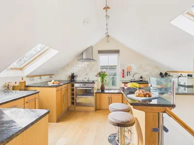 a large kitchen with wooden cabinets and a counter at The Crows Nest – Sea View Retreat, Flushing Cornwall in Falmouth