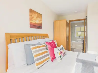 a bedroom with a white bed with colorful pillows at The Crows Nest – Sea View Retreat, Flushing Cornwall in Falmouth