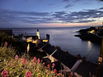 a view of a city with a clock tower and the water at Harbour Hideaway, Porthleven in Porthleven