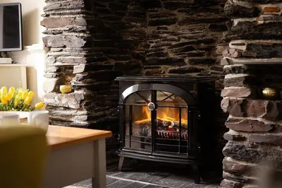 a fireplace in a room with a stone wall at Homelands in Port Isaac