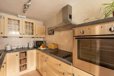 a kitchen with wooden cabinets and stainless steel appliances at Homelands in Port Isaac