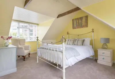 a bedroom with a bed and a chair at Poplar Cottage in Port Isaac