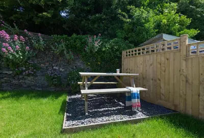 a wooden bench sitting next to a wooden fence at Poplar Cottage in Port Isaac