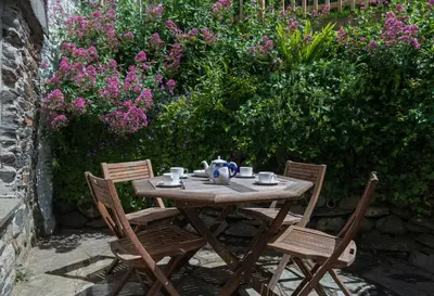 a wooden table with two chairs and a tea kettle on it at Poplar Cottage in Port Isaac