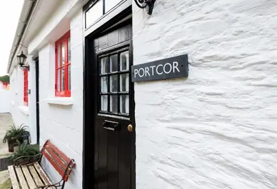 a sign on a building with a door and a bench at Portcor in Port Isaac