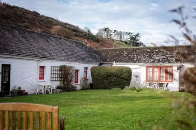 a white house with red windows and a yard at Portcor in Port Isaac