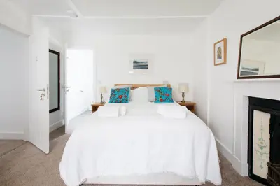 a white bedroom with a white bed and a fireplace at Ensuite room only in beautiful former farmhouse garden and parking in St Ives