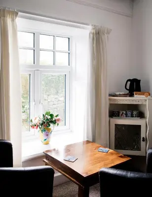 a living room with a table and a window at Ensuite room only in beautiful former farmhouse garden and parking in St Ives