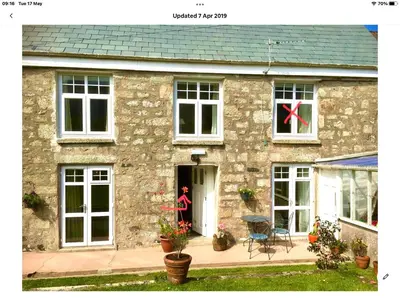 a stone house with a red bow in the window at Ensuite room only in beautiful former farmhouse garden and parking in St Ives