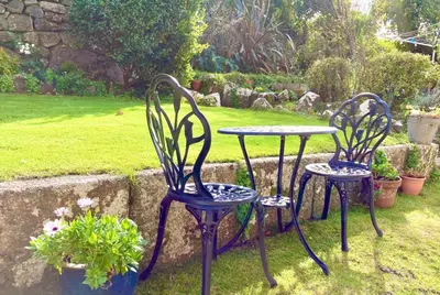 two chairs and a table in a garden at Ensuite room only in beautiful former farmhouse garden and parking in St Ives
