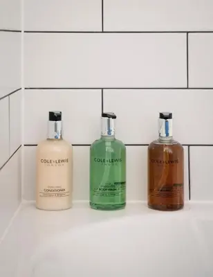 three bottles of soap on a shelf in a bathroom at Ensuite room only in beautiful former farmhouse garden and parking in St Ives