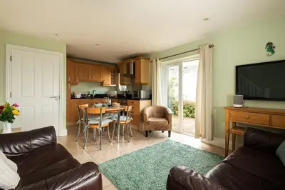 a living room with a couch and a kitchen with a table at White Horses in Port Isaac