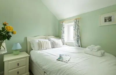 a bedroom with a white bed with towels on it at White Horses in Port Isaac