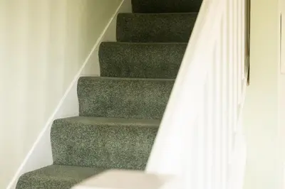 a stair case with a green carpeted staircase with a white curtain at White Horses in Port Isaac