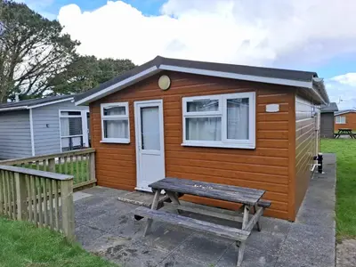 a tiny house with a picnic table in front of it at Cosy Corner Cabin in St Merryn